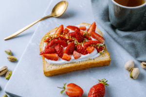 Photo d'une tranche de gâche sur laquelle il y a du fromage blanc et des tranches de fraises