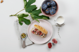 Photo d'un pain au lait frais dans une assiette, garnis de figues et de morceaux de pistaches.