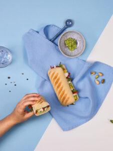 Deux pains panini La Boulangère cuisinés avec du poisson. Une main tient un des deux panini pour le manger.